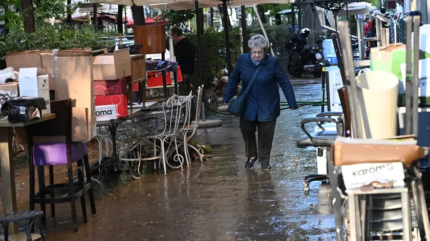 Un passante cammina accanto ai mobili sistemato dai proprietari di attività commerciali impegnati a ripilirei i propri locali parzialmente allagati dal violento temporale che si è abbattuto la scorsa notte su Milano e sulla Brianza, Milano., 31 ottobre 2023. ANSA/DANIEL DAL ZENNARO