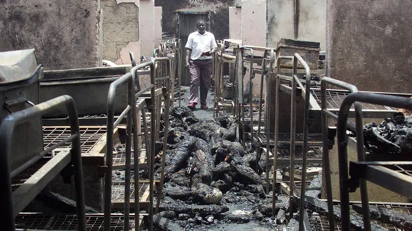 A man walks through the dormitory of Kyanguli Secondary School containing the burned corpses of dozens of students in Machakos east of Nairobi March 26, 2001. A Kenyan police officer said he suspected arson caused a fire that killed 58 teenaged boys. REUTERS/Antony Njuguna