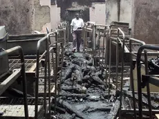 A man walks through the dormitory of Kyanguli Secondary School containing the burned corpses of dozens of students in Machakos east of Nairobi March 26, 2001. A Kenyan police officer said he suspected arson caused a fire that killed 58 teenaged boys. REUTERS/Antony Njuguna