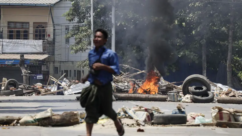epa09711494 (19/31) (FILE) - A man runs past a burning a roadblock set on fire by military personnel at a railway staff compound during a raid in Yangon, Myanmar, 10 March 2021 (reissued 27 January 2022). On 01 February 2021 the Myanmar Army arrested democratically elected political leaders and seized control of the country. Protests erupted nationwide leading to violent clashes and a military retaliation that had left at least 1,000 dead within the first six months. According to the United Nations, by early December 2021 over 280,000 people were still internally displaced in Myanmar due to armed clashes and insecurity. EPA/STRINGER ATTENTION: This Image is part of a PHOTO SET