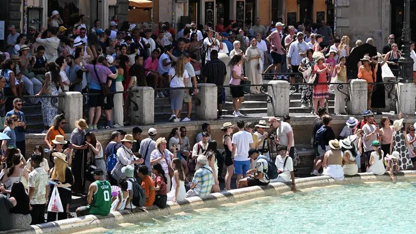 Turisti nella morsa del caldo a Fontana di Trevi. Roma, 13 agosto 2024. ANSA/CLAUDIO PERI