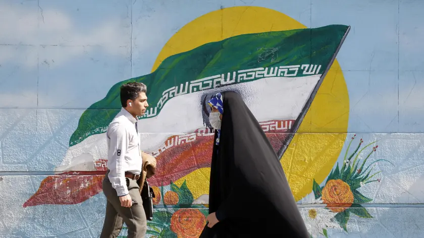 epa10493674 Iranians walk past next to a wall painting of Iran's national flag in downtown Tehran, Iran, 27 February 2023. According to Isna news agency, Iranian foreign minister Amir-Abdoulahian on 26 February 2023 said that Iran is close to reach a nuclear deal with US, after receiving a message from US through Iraq. Iran faces an economic crisis after its currency dropped to its lowest value against the US dollar and other foreign currencies last week, following sanctions imposed by the US and EU, amid tensions over nuclear talks, which have stopped in the wake of recent anti-government protests in the country. EPA/ABEDIN TAHERKENAREH