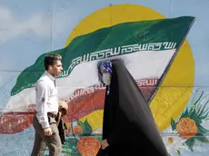 epa10493674 Iranians walk past next to a wall painting of Iran's national flag in downtown Tehran, Iran, 27 February 2023. According to Isna news agency, Iranian foreign minister Amir-Abdoulahian on 26 February 2023 said that Iran is close to reach a nuclear deal with US, after receiving a message from US through Iraq. Iran faces an economic crisis after its currency dropped to its lowest value against the US dollar and other foreign currencies last week, following sanctions imposed by the US and EU, amid tensions over nuclear talks, which have stopped in the wake of recent anti-government protests in the country. EPA/ABEDIN TAHERKENAREH
