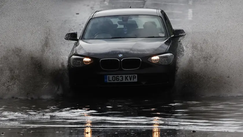 epa11620244 A car drives through flood water as water splashes up in London, Britain, 23 September 2024. Environment Agency issued a flood warning for parts of England as heavy rain is expected. EPA/NEIL HALL