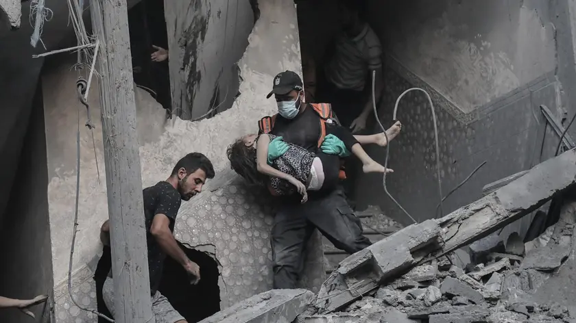 epa10926777 A child is recovered from the rubble of a residential building leveled in an Israeli airstrike, in Khan Younis refugee camp in the southern Gaza Strip, 19 October 2023. Israel has called for the evacuation of all civilians of northern Gaza ahead of an expected ground invasion. More than 1,400 Israelis have been killed and over 3,200 others injured, according to the IDF, after the Islamist movement Hamas launched an attack against Israel from the Gaza Strip on 07 October. More than 3,400 Palestinians have been killed and over 12,100 others injured in Gaza since Israel launched retaliatory air strikes, the Palestinian health ministry said. EPA/HAITHAM IMAD