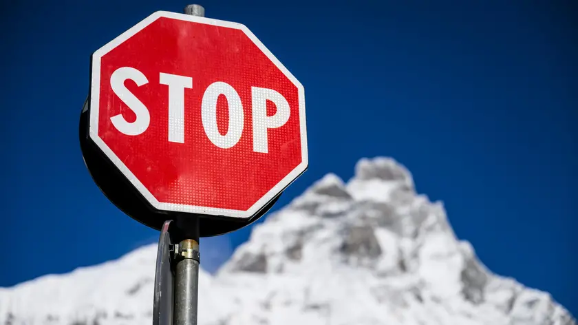 epa10976031 A stop sign is pictured front of the Matterhorn at the FIS Alpine Skiing World Cup event between Zermatt in Switzerland and Cervinia in Italy, 15 November 2023. The women's downhill training was cancelled due to strong winds. EPA/JEAN-CHRISTOPHE BOTT