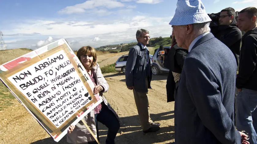 Il proprietario della discarica di Malagrotta, Manlio Cerroni, nell'area di Monti dell'Ortaccio, di fronte a lui una manifestante mostra un cartello contro la discarica, 29 ottobre 2012. ANSA/ MASSIMO PERCOSSI