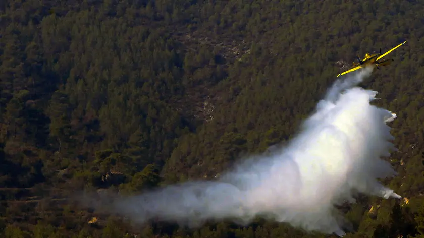 epa11511284 A firefighting plane drops water to cool the perimeter area of the Benasau forest fire in Alicante, Spain, 31 July 2024. Hundreds of people have been evacuated and roads have been cut off as a result of the fire. EPA/MORELL