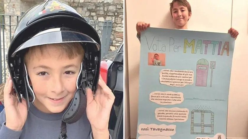 Mattia Cossettini con il casco dei vigili del fuoco e con il suo manifesto di candidatura