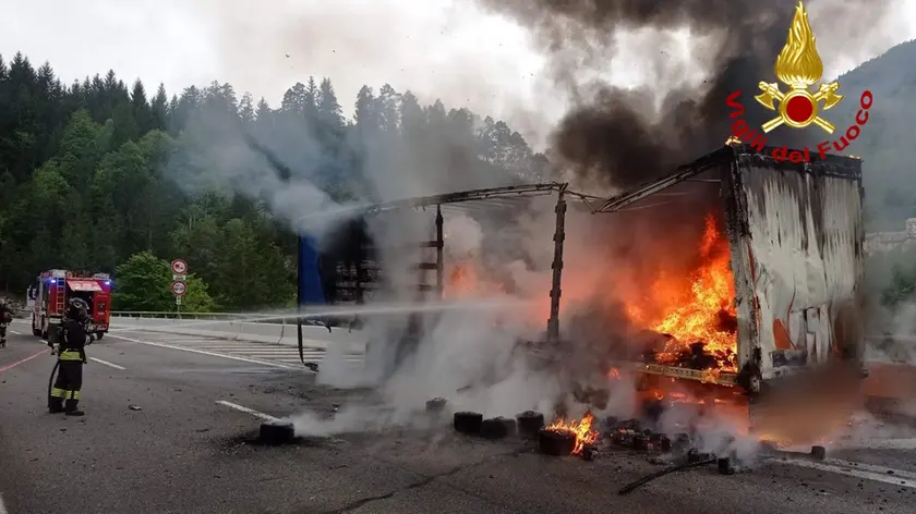 Il mezzo pesante distrutto dalle fiamme e i vigili del fuoco al lavoro per domare l'incendio