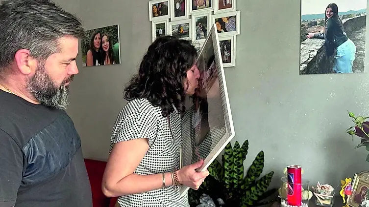 Mihaela Tritean, vicino al marito Ioan Cormos, tiene tra le mani un quadro con la foto della figlia e lo bacia