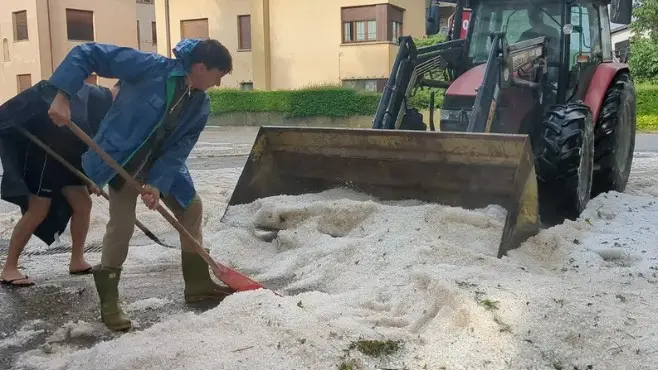 In un'immagine del 2023 i cittadini spalano via la grandine come fosse neve a Reana del Royale