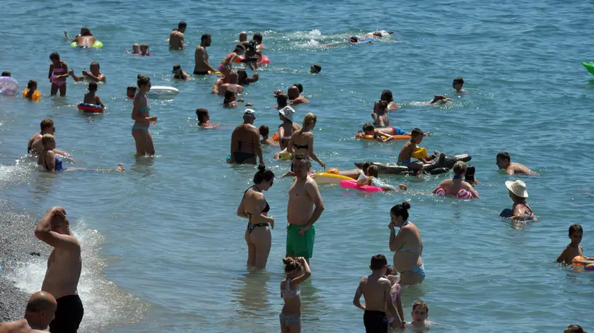 Bagnanti cercano refrigerio in acqua a Trieste. Foto Bruni