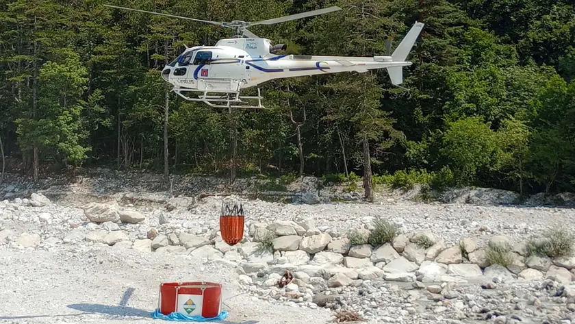 L'elicottero della Protezione civile recupera l'acqua per spegnere le fiamme