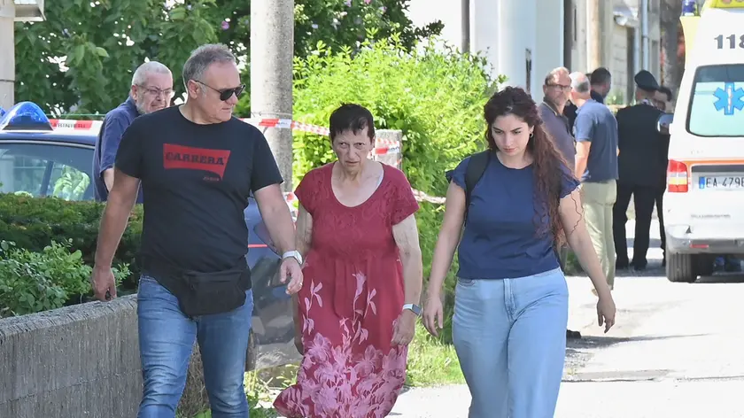 Al centro Lorena Venier, reo confessa dell'omicidio del figlio, mentre viene portata via dalla sua abitazione