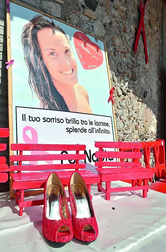 La foto di Nadia Orlando vicino a tre piccole panchine e a un paio di scarpe rosse