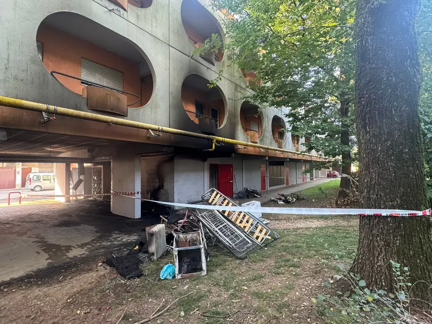 Il materiale incenerito dopo il rogo e i segni dell'incendio sul condominio