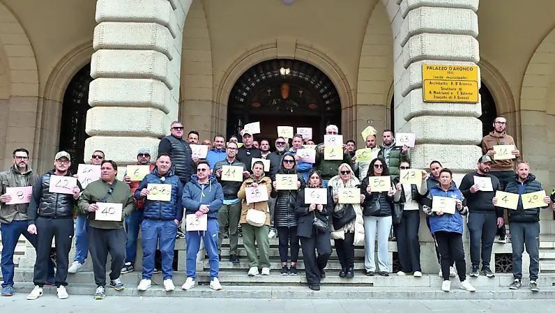 I partecipanti alla protesta, una quarantina di esercenti, che mostrano i cartelli con i numeri / foto petrussi
