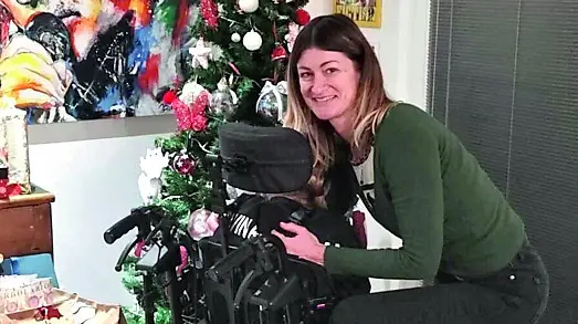 Asia sulla carrozzina davanti all’albero di Natale con la mamma Milena