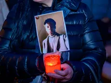 Una partecipante alla fiaccolata in ricordo di Paul Nana Ampong,a largo Cervignano, tiene in mano la foto del 15enne e un luminO