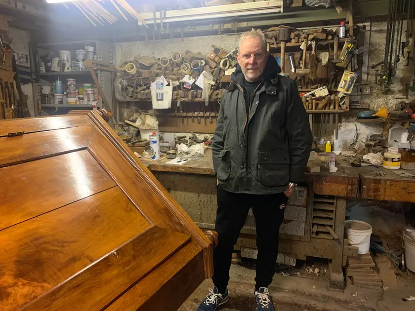 Andrea Crestan nel suo laboratorio in corso Vittorio Emanuele: a sinistra un mobile angolare da restaurare