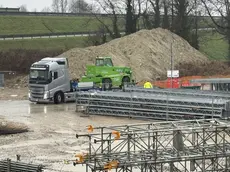 I tir portano via i macchinari dal cantiere della bretella (Foto Porcile)