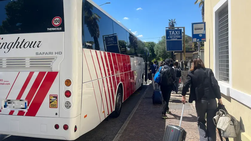 Un bus sostitutivo fuori dalla stazione di Cervignano e i viaggiatori in attesa