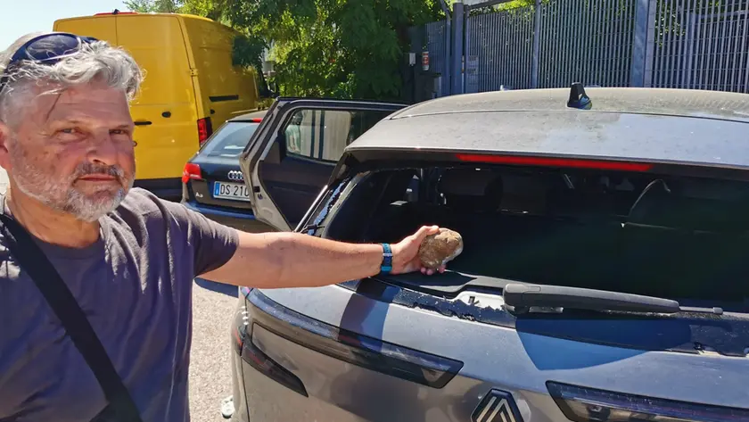 Lodolo mostra il sasso che ha rotto il vetro della sua auto
