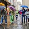 Un gruppo di turisti si ripara dalla pioggia in via San Sebastiano a Trieste (foto Andrea Lasorte)