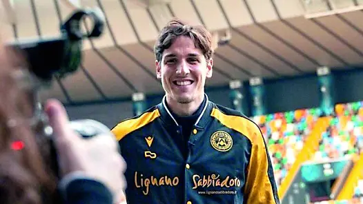 Nicolò Zaniolo sorridente con la tuta dell’Udinese