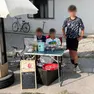 I tre amici dietro al loro banchetto con limonata, caffè e dolcetti