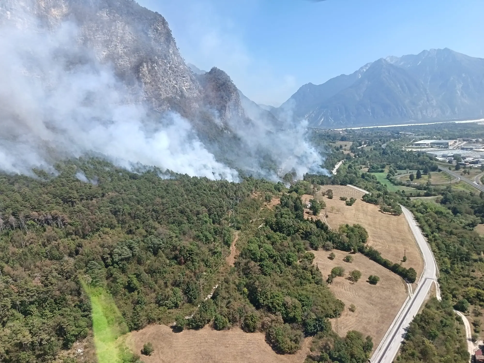 Le colonne di fumo degli incendi che stanno bruciando in Carnia sono visibili a chilometri di distanza e in alcune zone l’aria è diventata difficile da respirare. Una coltre grigia avvolge vallate e montagne, oscurando il cielo e cambiando il volto del paesaggio. Nella notte appena trascorsa, nel buio erano le fiamme sui versanti a illuminare la montagna, mentre con il giorno il fumo è tornato a dominare lo scenario.
