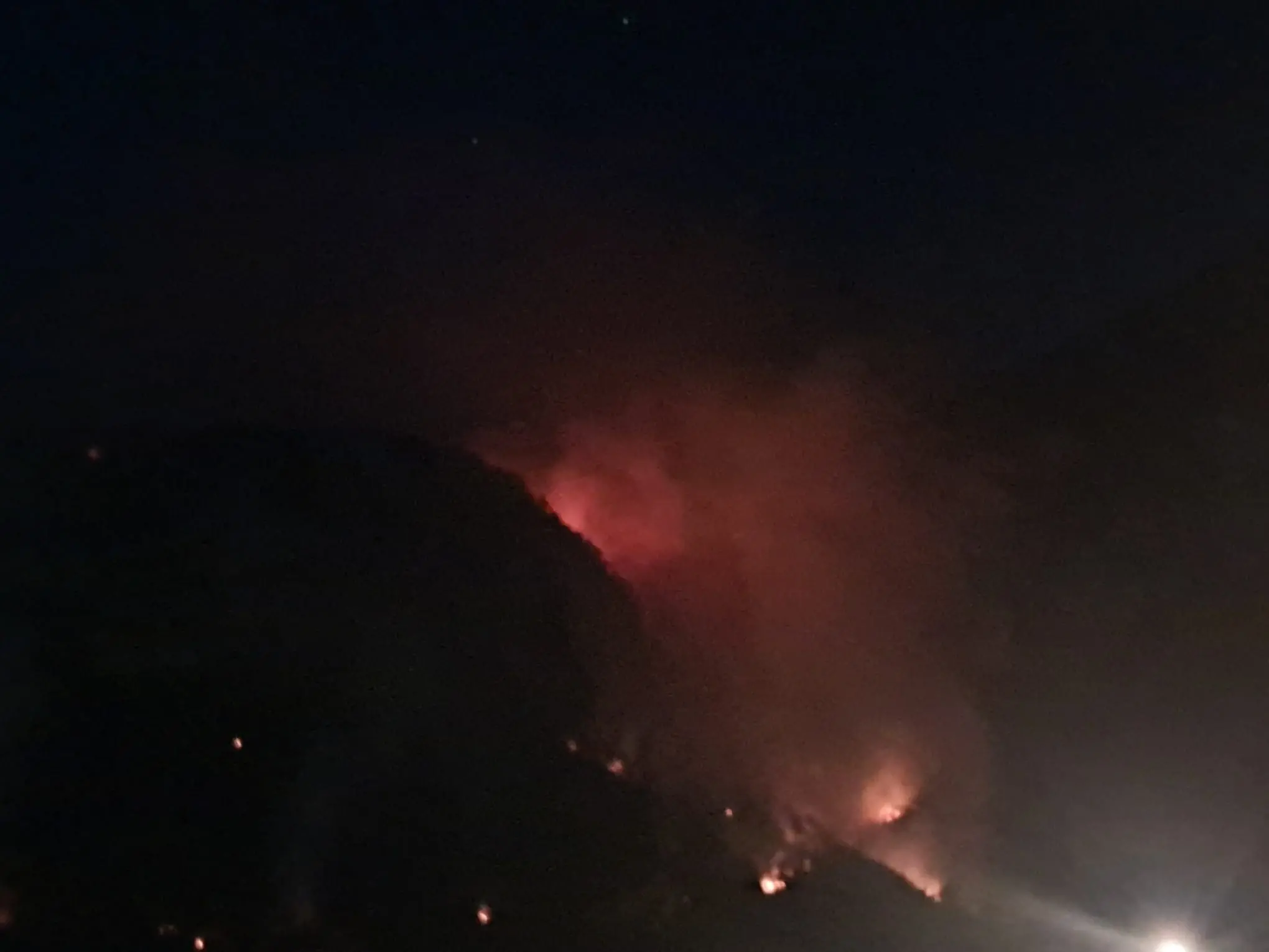 Le colonne di fumo degli incendi che stanno bruciando in Carnia sono visibili a chilometri di distanza e in alcune zone l’aria è diventata difficile da respirare. Una coltre grigia avvolge vallate e montagne, oscurando il cielo e cambiando il volto del paesaggio. Nella notte appena trascorsa, nel buio erano le fiamme sui versanti a illuminare la montagna, mentre con il giorno il fumo è tornato a dominare lo scenario.