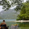 I turisti lungo le sponde del lago di Cavazzo mentre il canadair raccoglie l'acqua per spegnere gli incendi