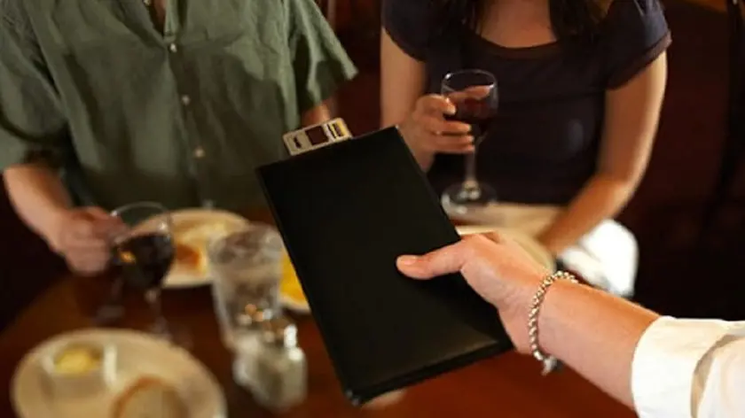 Un cameriere presenta il conto del pranzo in un ristorante.