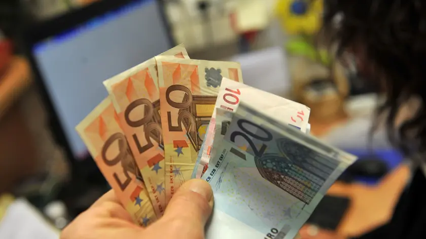Una persona tiene in mano alcune banconote di euro, in una immagine del 05 dicembre 2011 a Lucca. Le retribuzioni contrattuali orarie a novembre restano ferme su ottobre mentre aumentano dell'1,5% su base annua. Lo rileva l'Istat, aggiungendo che la crescita tendenziale e' la piu' bassa dall'ottobre del 2010, ovvero da oltre un anno, quando si registro' lo stesso dato che risulta il minimo da marzo 1999..ANSA/FRANCO SILVI