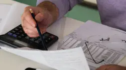 Mature man sitting at desk checking bills, close-up