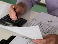 Mature man sitting at desk checking bills, close-up