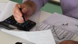 Mature man sitting at desk checking bills, close-up