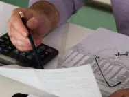 Mature man sitting at desk checking bills, close-up