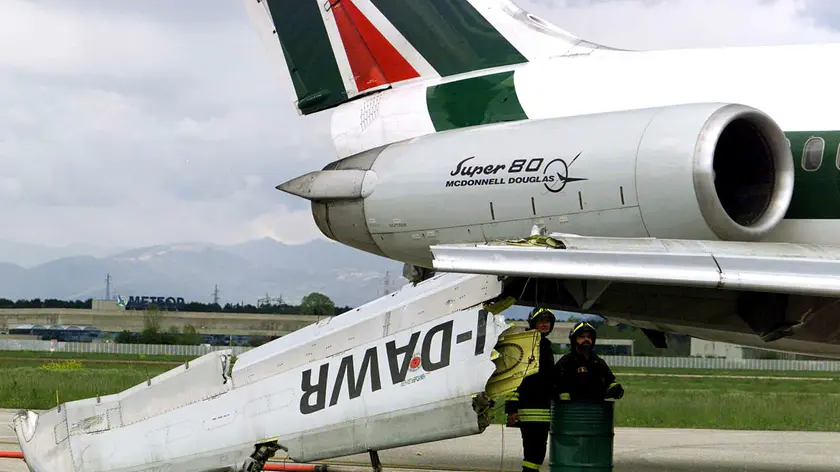 I vigili del fuoco osservano i danni riportati dall' aereo MD80 dell' Alitalia dopo l'urto con un autocarro che si trovava nella zona fra la pista di atterraggio e il piazzale