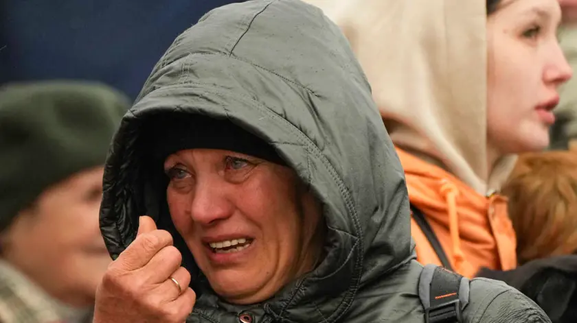 A woman reacts as she waits in a line after fleeing the war from neighbouring Ukraine at the border crossing in Medyka, southeastern Poland, Tuesday, April 5, 2022. (AP Photo/Sergei Grits)