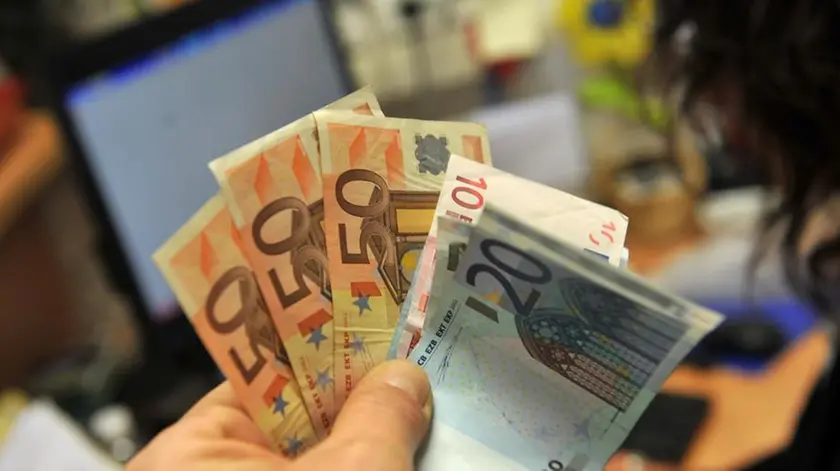 Una persona tiene in mano alcune banconote di euro, in una immagine del 05 dicembre 2011 a Lucca. Le retribuzioni contrattuali orarie a novembre restano ferme su ottobre mentre aumentano dell'1,5% su base annua. Lo rileva l'Istat, aggiungendo che la crescita tendenziale e' la piu' bassa dall'ottobre del 2010, ovvero da oltre un anno, quando si registro' lo stesso dato che risulta il minimo da marzo 1999..ANSA/FRANCO SILVI
