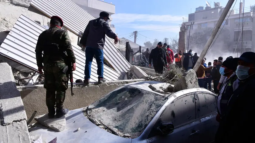 epa11091713 Soldiers and people check a damaged car at the site of residential building that was targeted in an alleged Israeli strike in Mezzah neighborhood, Damascus, Syria, 20 January 2024. According to Syrian state-run media, at least five people were killed in an Israeli attack targeting a residential building in Mezzah neighborhood in Damascus on 20 January. The Israeli army did not comment on the event. EPA/STR