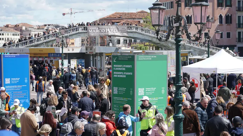 Operatori ai varchi controllano il ticket di accesso sul telefonino dei turisti, al check point del piazzale della stazione ferroviaria di Venezia