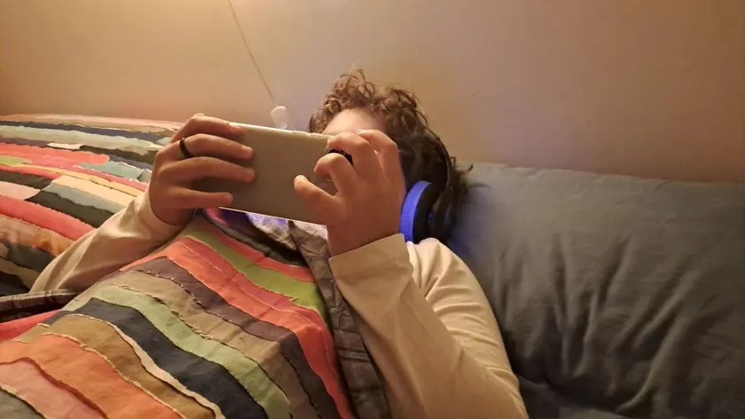 Un bambino di 11 anni usa il cellulare per guardare un film mentre è a letto in camera sua, Roma, 15 novembre 2023. ANSA / CARMELA GIUDICE (cellulare, telefonino, bambino, bambini, bimbi, bimbo, generica, simbolica, youtube, challenge, internet)