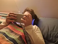 Un bambino di 11 anni usa il cellulare per guardare un film mentre è a letto in camera sua, Roma, 15 novembre 2023. ANSA / CARMELA GIUDICE (cellulare, telefonino, bambino, bambini, bimbi, bimbo, generica, simbolica, youtube, challenge, internet)