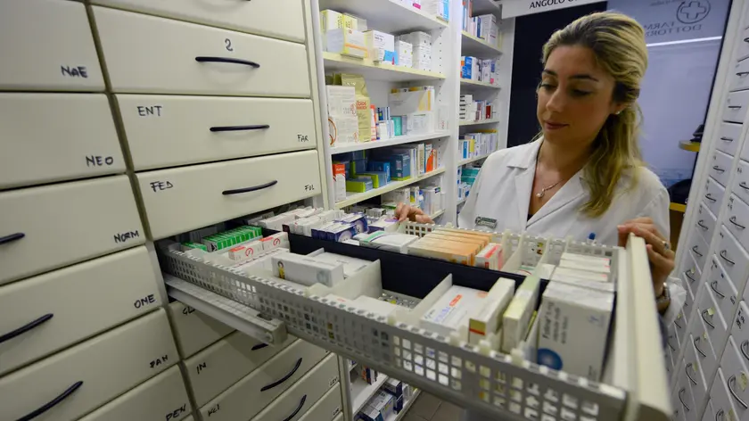 Una farmacista con un cassetto di medicinali aperto in una farmacia a Pontedera, Pisa, 10 luglio 2012. ANSA/STRINGER