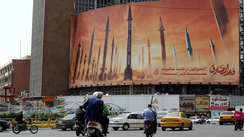 epa11293860 Iranians drive near an anti-Israel billboard carrying pictures of Iranian missiles and a sentence reading in Persian 'Israel is weaker than spider home' in Tehran, Iran, 22 April 2024. Tension between Iran and Israel continue since Iran's Islamic Revolutionary Guards Corps (IRGC) launched drones and missiles towards Israel on 13 April, following an airstrike on the Iranian embassy in Syria which Iran claimed was conducted by Israel. Iranian state media reported that three aerial objects were destroyed by air defense systems over the central city of Isfahan early morning on 19 April. EPA/ABEDIN TAHERKENAREH