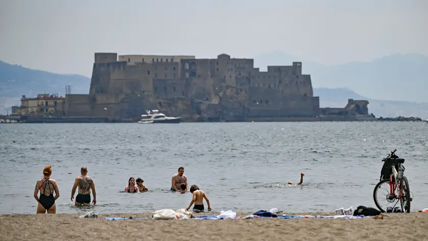 Gente in spiaggia e turisti in giro in bici a Napoli in una giornata caratterizzata da sole e temperatura estiva 15 maggio 2024. ANSA/ CIRO FUSCO